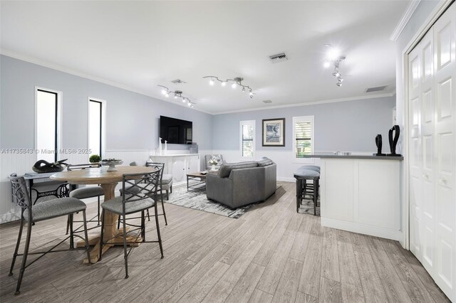 living area featuring visible vents, ornamental molding, rail lighting, and light wood finished floors