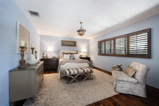 bedroom with wood finished floors, visible vents, and baseboards