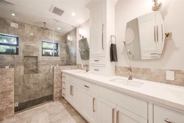 full bath with a sink, visible vents, double vanity, and a shower stall