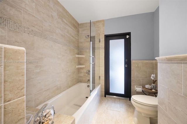 bathroom with toilet, tub / shower combination, and tile walls