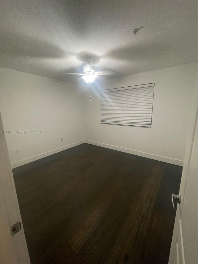 empty room with dark wood-type flooring, ceiling fan, and a textured ceiling