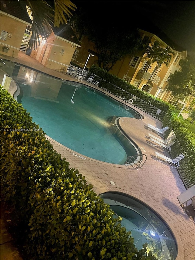 pool at night featuring a patio area