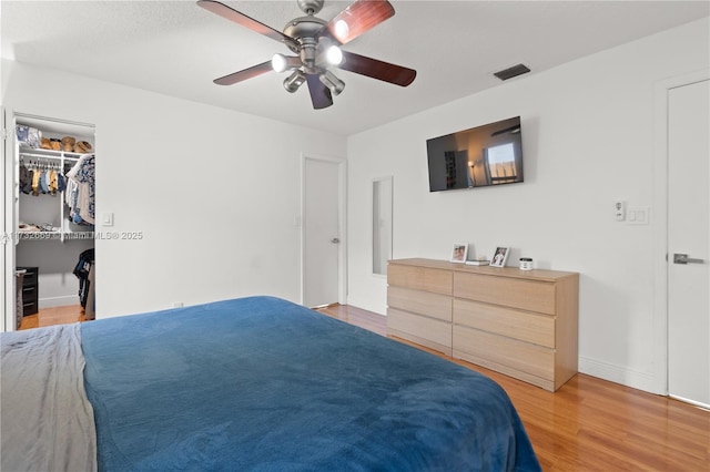 bedroom featuring ceiling fan, a spacious closet, and light hardwood / wood-style floors