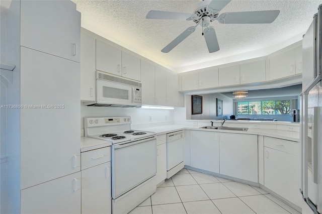 kitchen with sink, a textured ceiling, light tile patterned floors, white appliances, and white cabinets