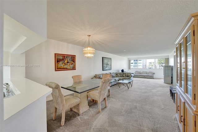 dining space featuring light carpet, a notable chandelier, and a textured ceiling