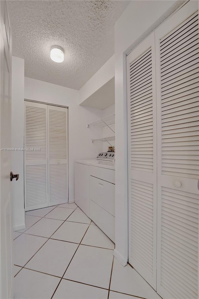 corridor featuring light tile patterned flooring, washer and dryer, and a textured ceiling