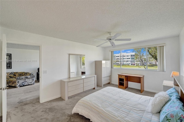 bedroom with ceiling fan, light carpet, and a textured ceiling