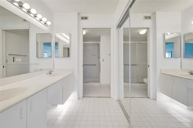 bathroom featuring a shower with shower door, tile patterned floors, a textured ceiling, and toilet