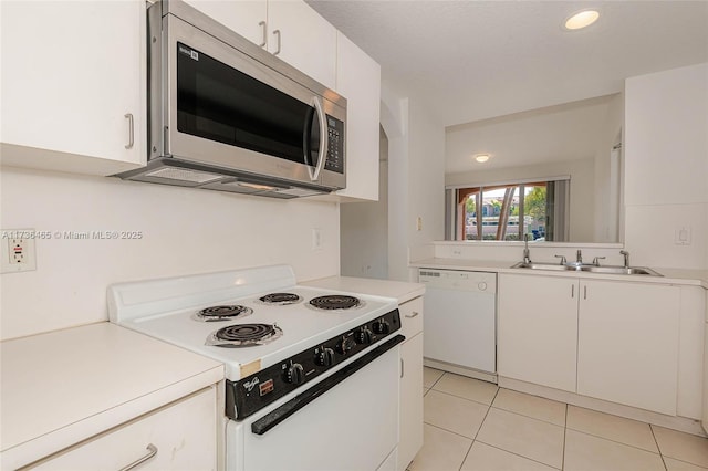 kitchen with sink, light tile patterned floors, white cabinets, and white appliances