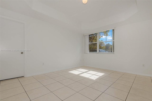 unfurnished room featuring a raised ceiling and light tile patterned flooring