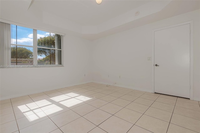 empty room featuring light tile patterned floors and a tray ceiling