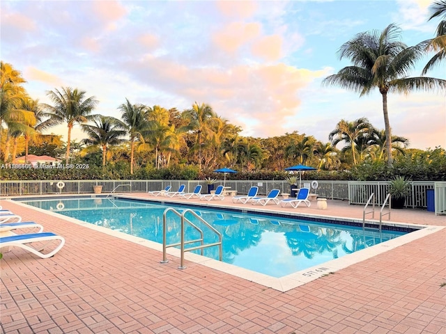 pool at dusk featuring a patio area