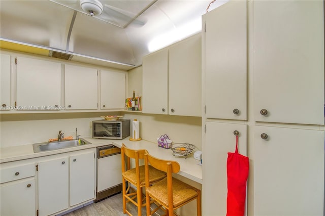 kitchen featuring white cabinetry, sink, white dishwasher, and light hardwood / wood-style flooring