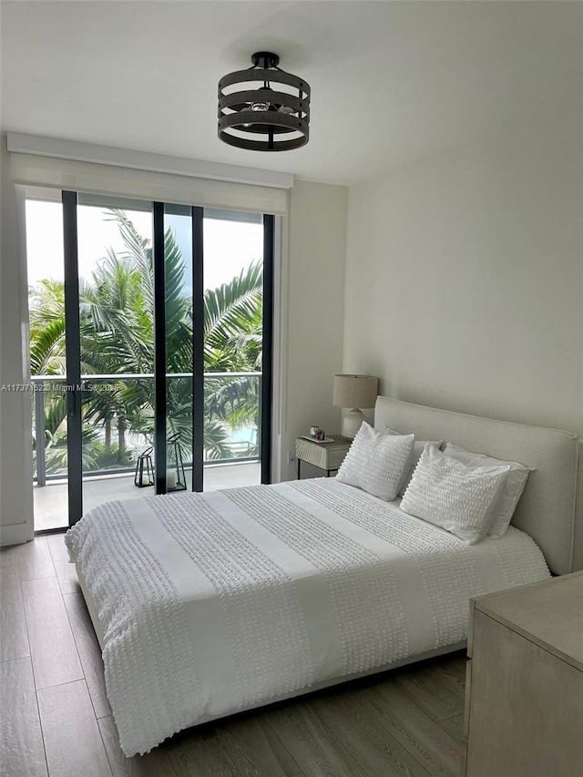 bedroom with wood-type flooring, access to exterior, and multiple windows