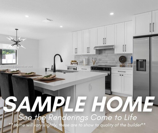 kitchen featuring sink, white cabinetry, tasteful backsplash, a center island with sink, and stainless steel appliances