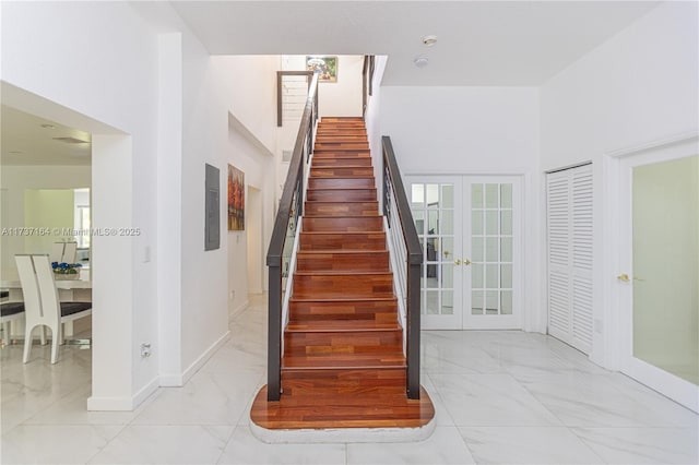 staircase featuring french doors and a towering ceiling