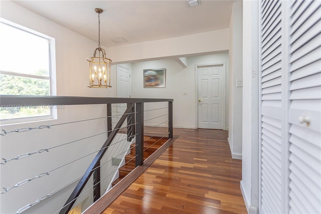 hall with dark hardwood / wood-style floors and a notable chandelier