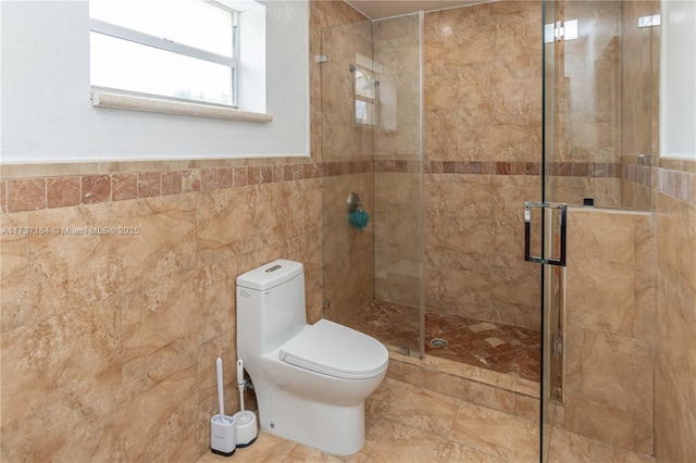 bathroom with toilet, a shower with shower door, and tile walls