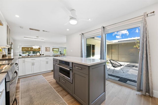 kitchen with hanging light fixtures, oven, white cabinets, and kitchen peninsula