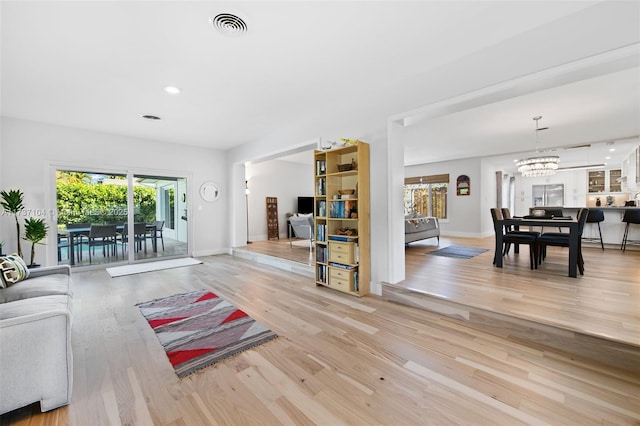 living room with light wood-type flooring and a chandelier