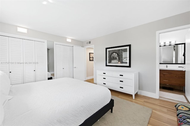 bedroom featuring connected bathroom, multiple closets, and light wood-type flooring