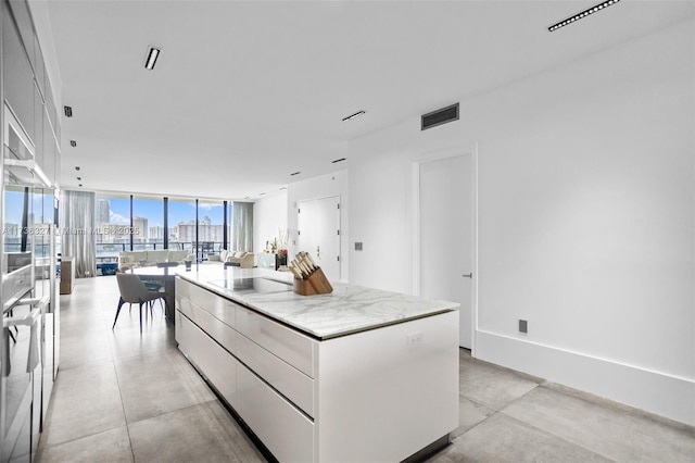 kitchen with white cabinetry, floor to ceiling windows, black electric cooktop, and a kitchen island