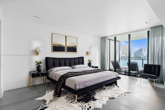 bedroom featuring access to exterior, floor to ceiling windows, and a water view