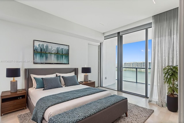 bedroom featuring floor to ceiling windows, access to exterior, and light hardwood / wood-style flooring