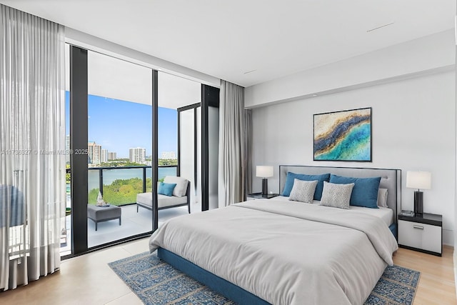 bedroom featuring a water view, a wall of windows, and access to outside