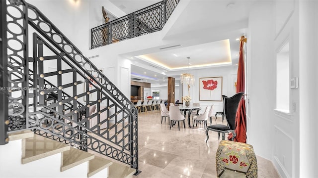 staircase featuring a towering ceiling, a tray ceiling, and a chandelier