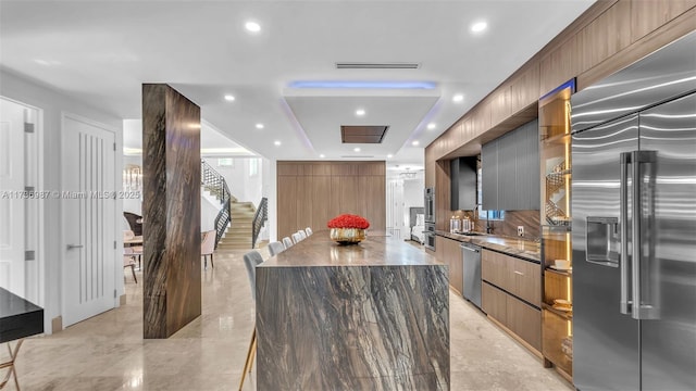 kitchen with stainless steel appliances, tasteful backsplash, sink, and a spacious island