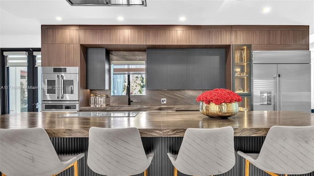 kitchen with sink, decorative backsplash, stainless steel appliances, and a kitchen breakfast bar