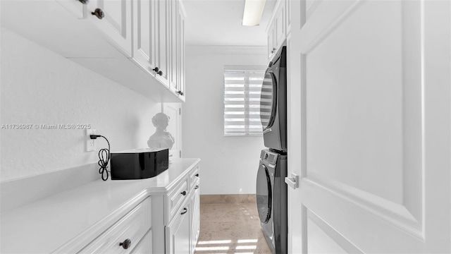 laundry room with cabinets, stacked washing maching and dryer, and ornamental molding