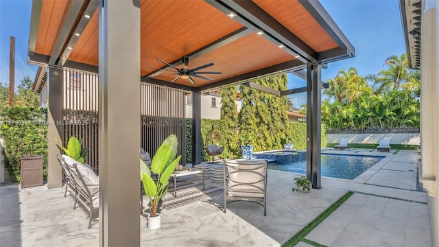 view of patio featuring ceiling fan and a pool with hot tub