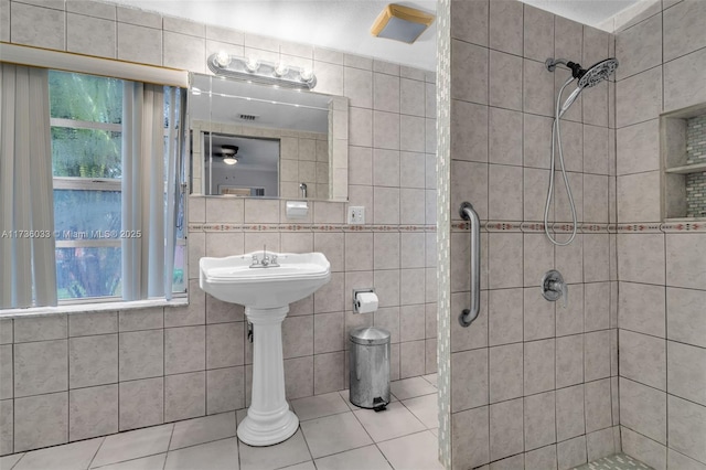 bathroom with tile walls, tile patterned flooring, and a tile shower