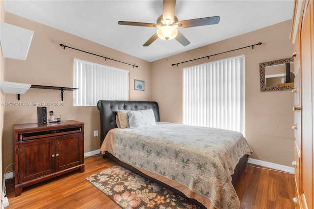 bedroom with ceiling fan, multiple windows, and light wood-type flooring