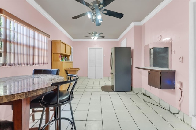 kitchen with light tile patterned flooring, ornamental molding, and stainless steel fridge