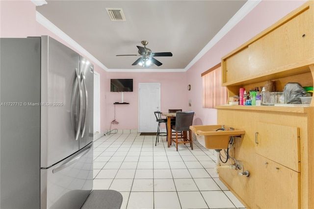 kitchen featuring crown molding, light tile patterned flooring, stainless steel fridge, and light brown cabinetry