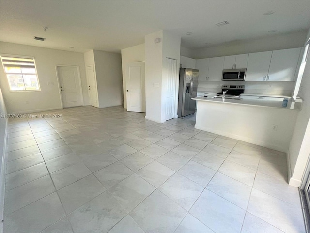 kitchen featuring appliances with stainless steel finishes, white cabinets, and kitchen peninsula