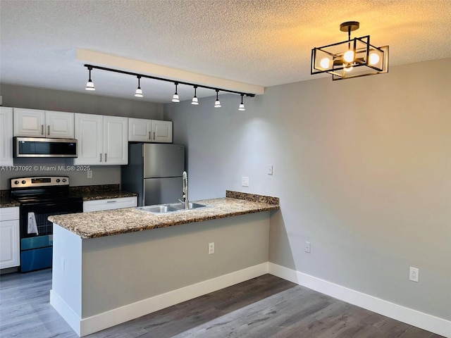 kitchen featuring sink, white cabinetry, hanging light fixtures, stainless steel appliances, and kitchen peninsula