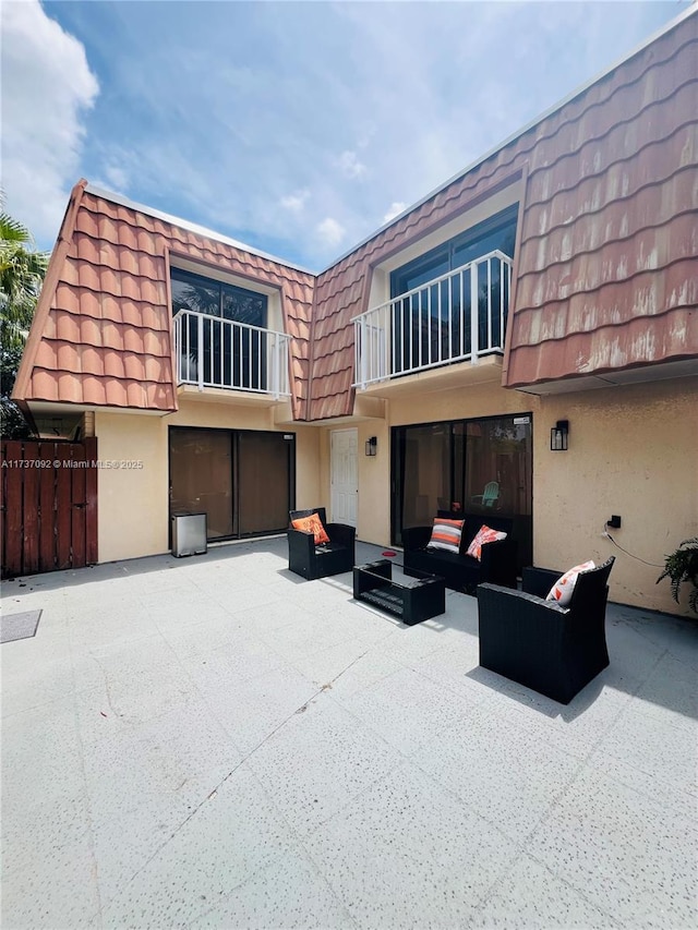 529 Green Springs Pl, West Palm Beach, FL 33409 - back of property with an outdoor hangout area, a balcony, mansard roof, stucco siding, and a patio