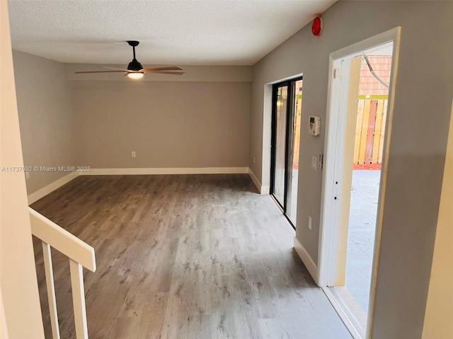 empty room with ceiling fan, a textured ceiling, and light wood-type flooring