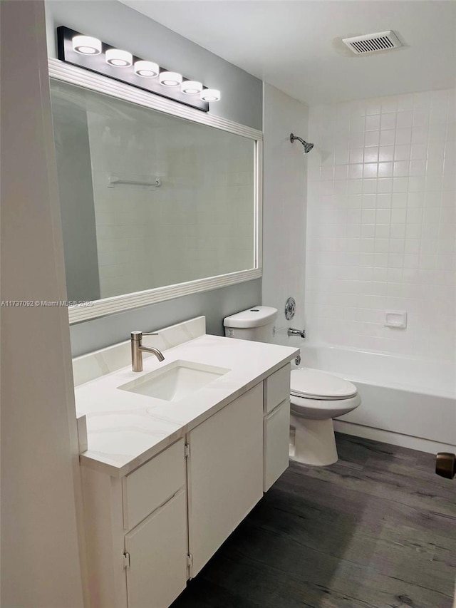 full bathroom with vanity, toilet, tiled shower / bath combo, and hardwood / wood-style floors