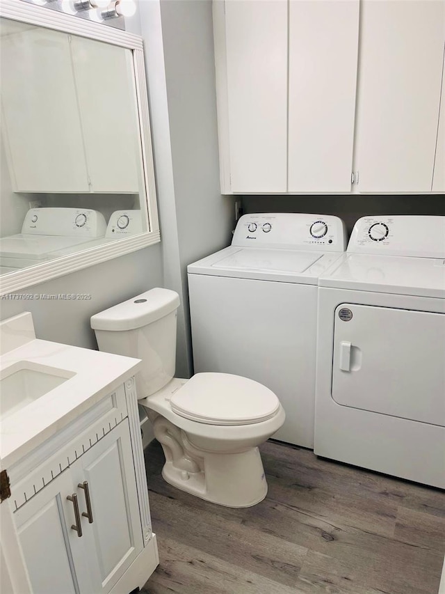 bathroom featuring vanity, toilet, separate washer and dryer, and hardwood / wood-style floors