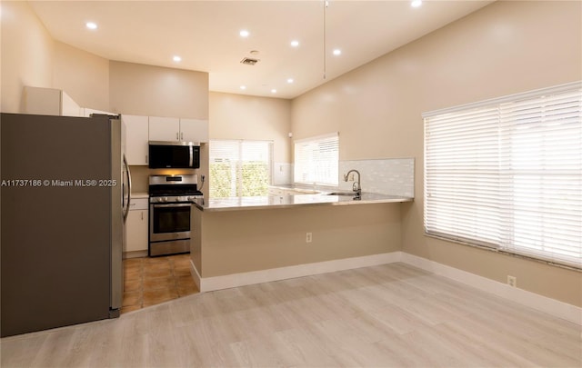 kitchen featuring white cabinetry, sink, stainless steel appliances, and kitchen peninsula