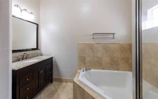 bathroom with vanity, a relaxing tiled tub, and tile patterned floors