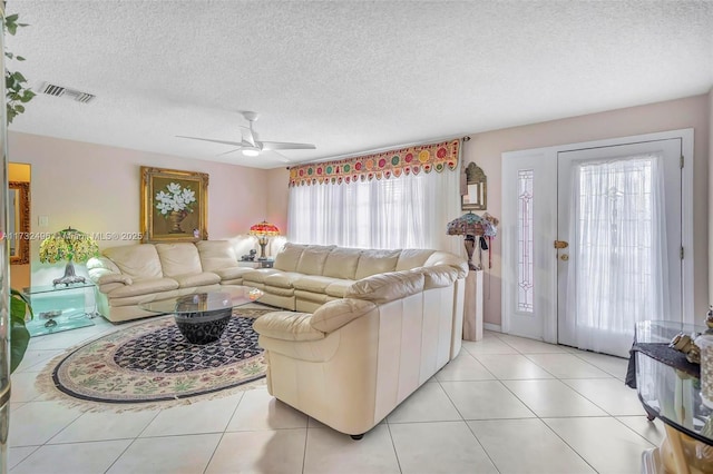 living room with light tile patterned flooring, ceiling fan, and a textured ceiling