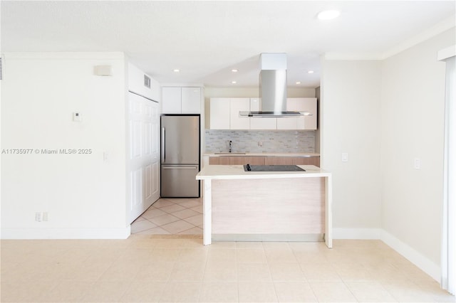 kitchen with sink, white cabinetry, stainless steel fridge, island exhaust hood, and backsplash