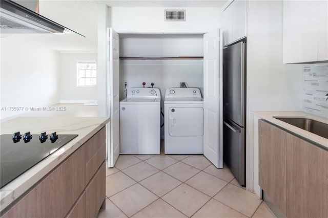 laundry room featuring sink, light tile patterned floors, and independent washer and dryer