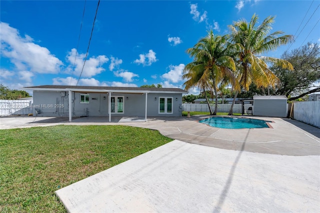 rear view of property with a fenced in pool, a lawn, french doors, and a patio area